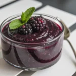 A bowl of fresh blackberry puree with a smooth texture, garnished with blackberries and mint.